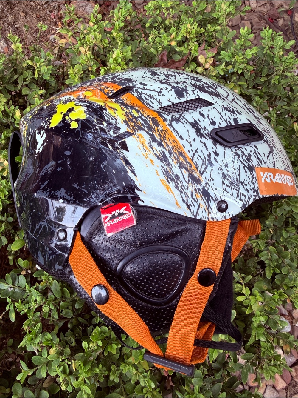 Kranked snow sports helmet with an orange and black splattered design S/M